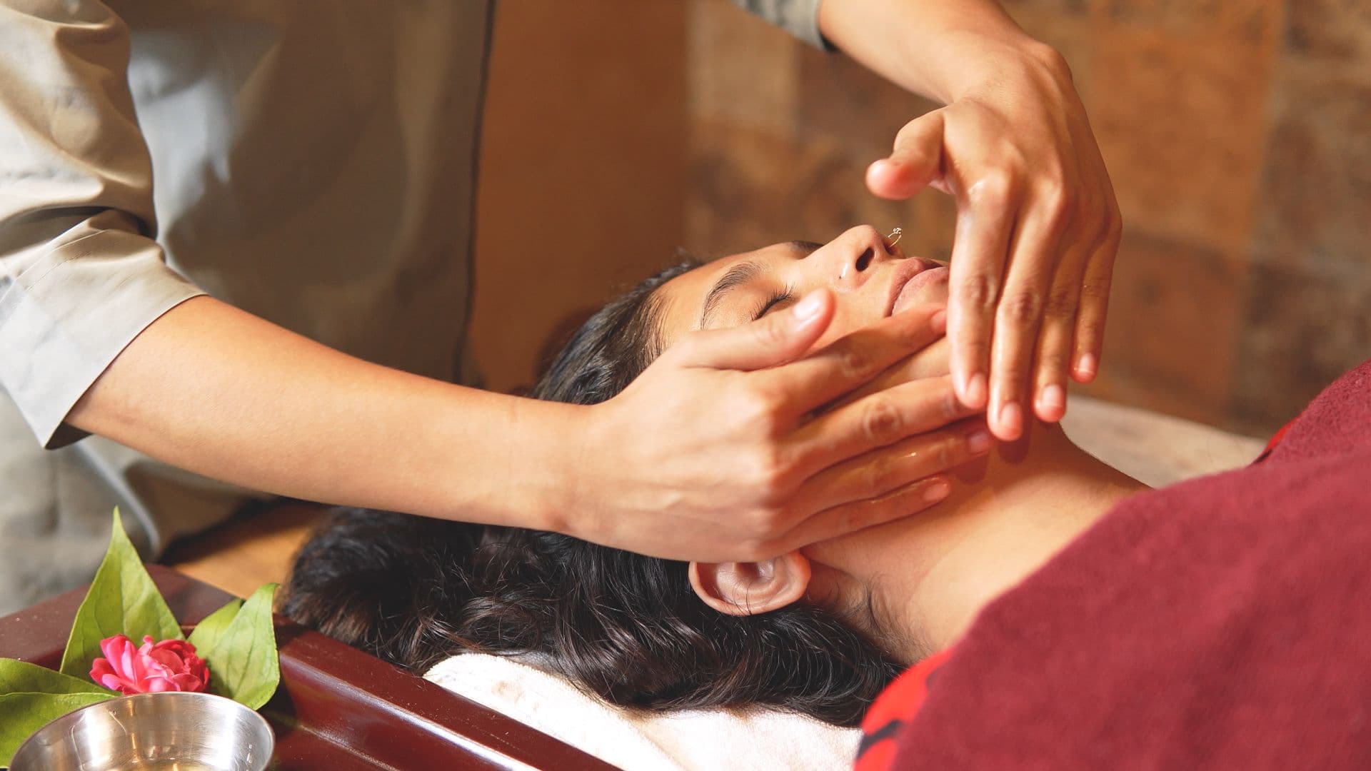 Hands performing a facial massage during an Ayurveda therapy session at Atmabodh Wellness Center